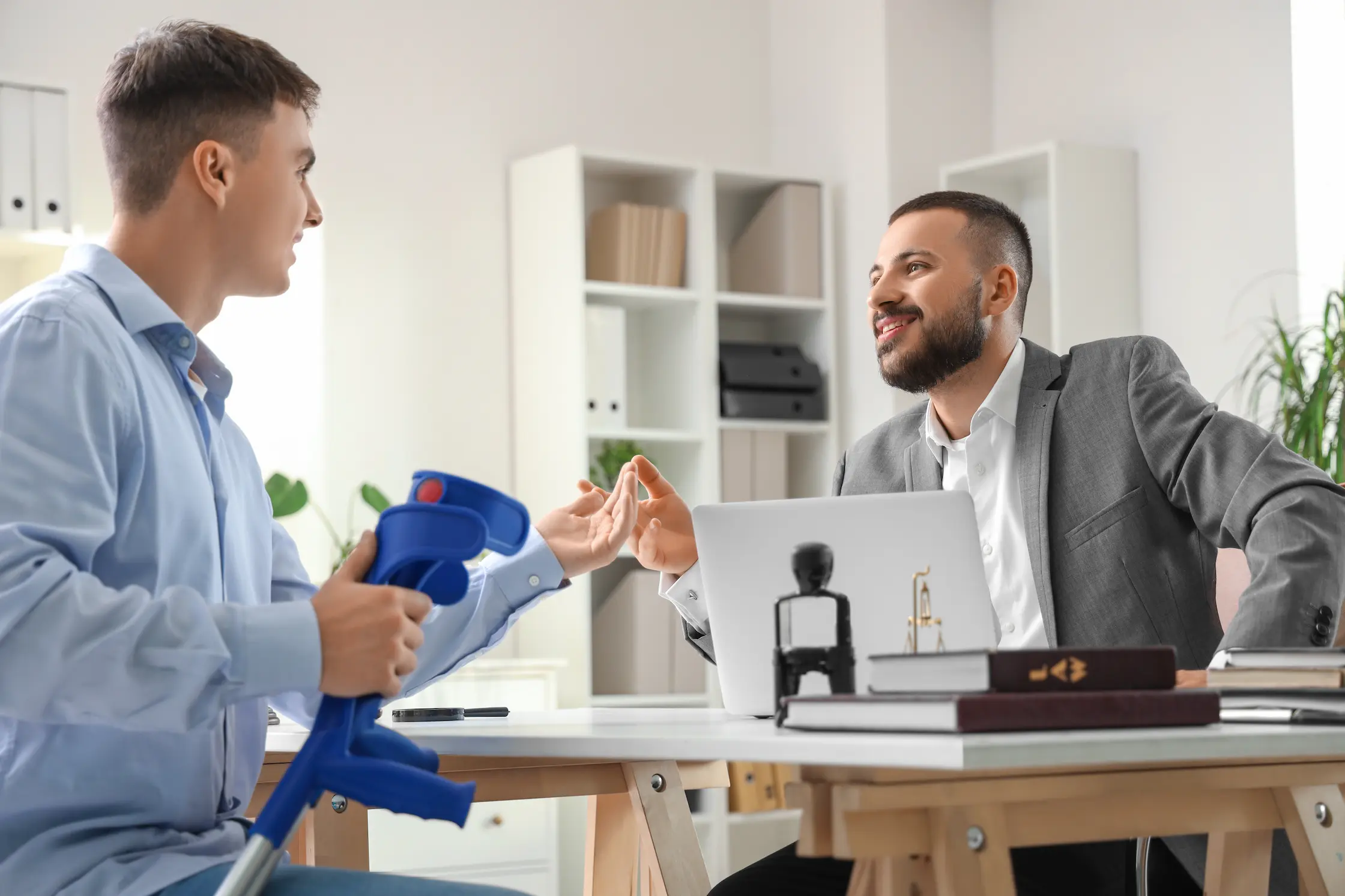 Male lawyer consulting man with crutches in office