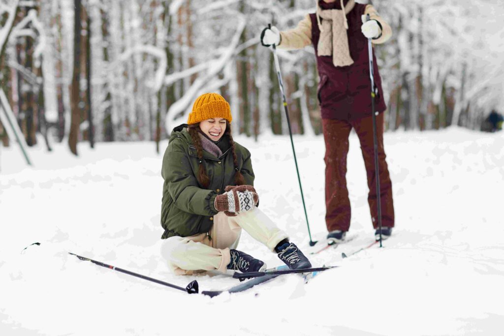 crying young woman sitting on snow injured during skiing