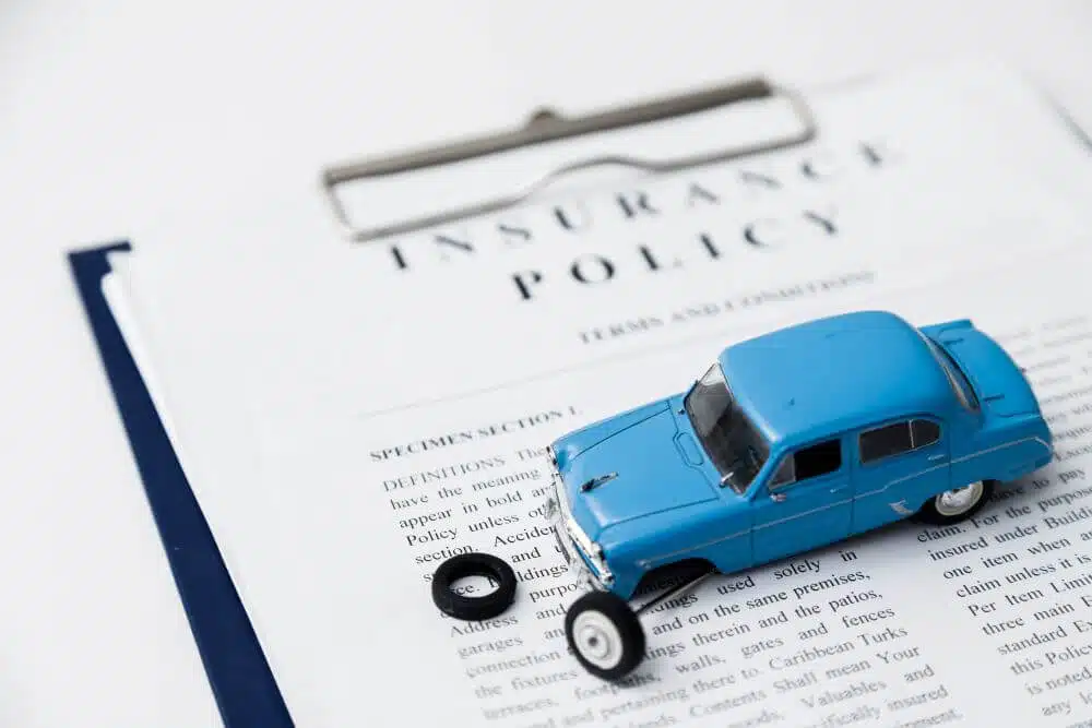 Blue toy car on an insurance policy contract - CGH Injury Lawyers