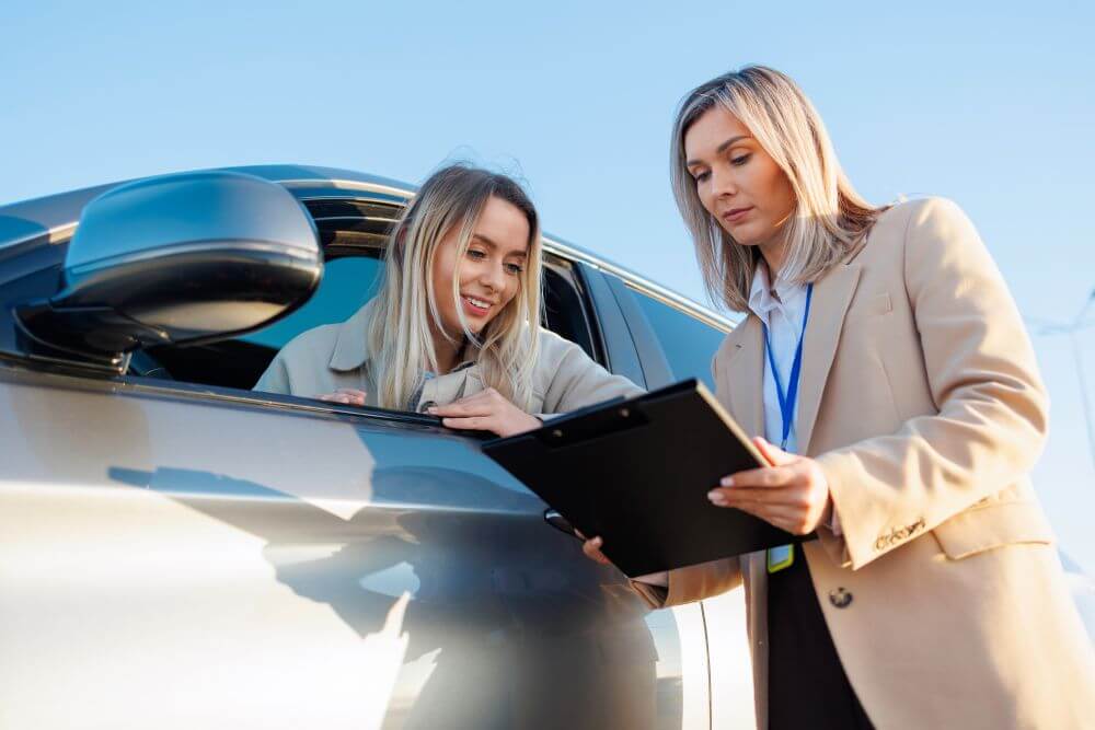 Woman inside a car talking to an insurance adjuster - CGH Injury Lawyers